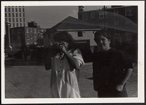 Two people, one with a camera taking a photograph at Newtowne Court