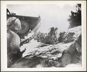 The first wave of marines to hit the Saipan beach in the Marianas invasion take cover behind a sand dune