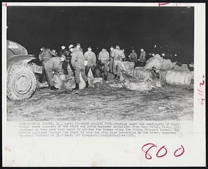 Race Against Time--Working under the headlights of their trucks these soldiers of the 201st and 199th Engineer Battalions from camp McCoy, Wisc., fill sandbags as they work last night to bolster the levees along the rising Missouri River. The battle continued through the night to save the city from inundation by the river, expected to crest Thursday at 31.5 feet.
