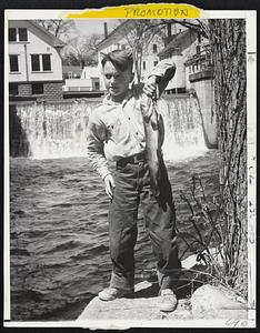 Maine Fish Story – Richard Truman, 9, of Norway, Me., holds the tow and one-half pound trout that he caught with bare hands in mill stream below dam in background. He saw the fish basking in the stream, waded in and made a lunge for the 20-inch beauty.