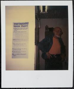 Man standing next to "photography room rules" sign