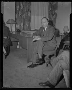 Former Minnesota Governor Harold Stassen seated next to desk