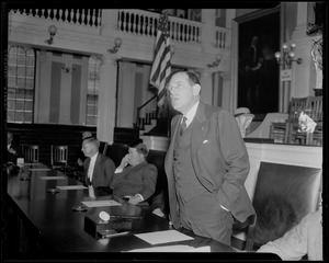 Robert Gardiner Wilson, Jr. speaking with others seated nearby and gavel in front of him