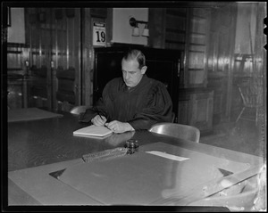 Judge Robert Gardiner Wilson, Jr., in robes, writing at desk
