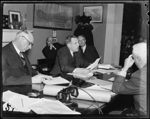 Robert Gardiner Wilson, Jr. having discussion with other men seated around table