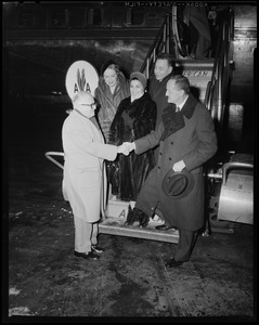 Italian Ambassador Manlio Brosio shaking hands with man near airplane as Earl Wilson and others look on