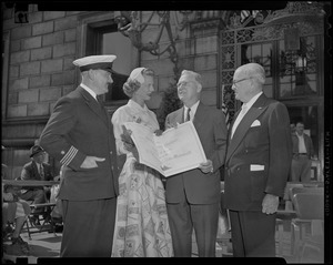 John B. Hynes standing outside of the Boston Public Library, Central Branch with three others and holding large certificate as part of city's 325th birthday celebrations
