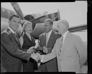 Jack Webb shaking hands with Boston Police Commissioner Thomas F. Sullivan and receiving honorary police badge, with wife Dorothy Towne Webb and city greeter Jack Brown in front of airplane