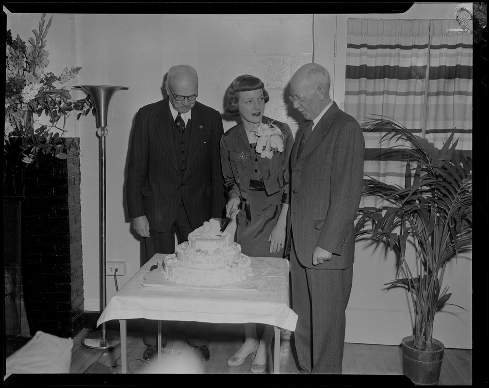 Tenley Albright, with two men, cutting cake decorated with figure skates