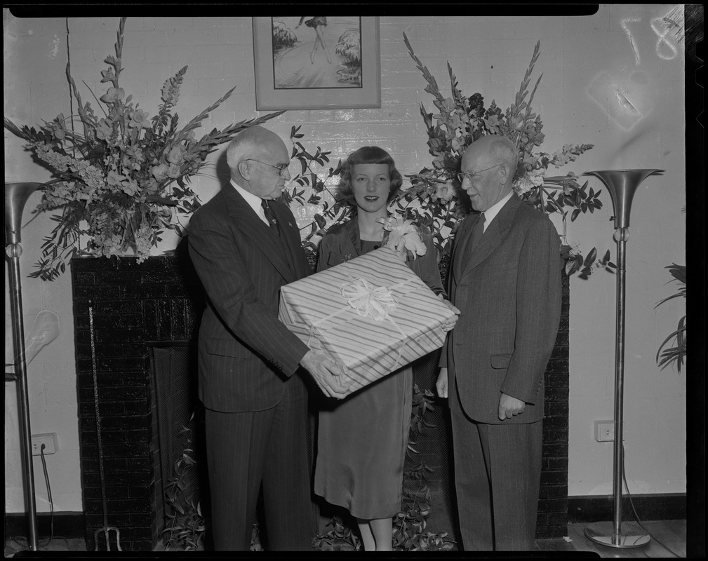 Tenley Albright with two men, holding a wrapped gift box