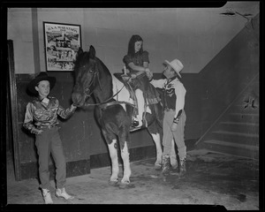 Gene Autry shaking hands with girl on horse, with boy standing nearby