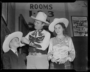Gene Autry adjusting cowboy hat on boy's head, with girl standing nearby