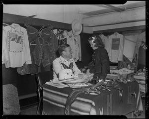 Gene Autry and little girl at desk with cowboy shirts hanging up in room