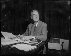 Governor-elect Christian Herter at desk, holding pencil