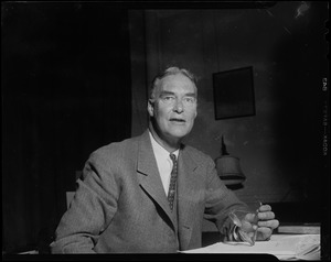 Governor-elect Christian Herter at desk, holding eyeglasses