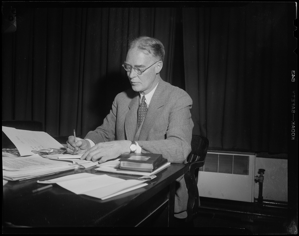 Governor-elect Christian Herter at desk, holding pencil