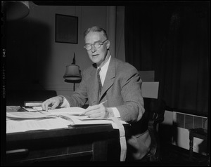 Governor-elect Christian Herter at desk, holding pencil