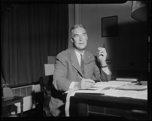 Governor-elect Christian Herter at desk, holding pencil and eyeglasses