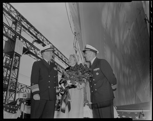 Sponsor Susan Bainbridge Goodale holding bouquet and standing with two naval officers at the launch of USS Bainbridge from shipyard in Quincy