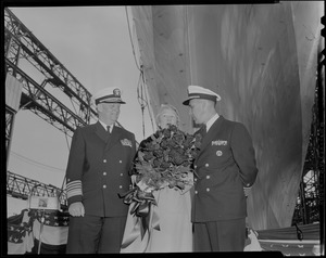 Sponsor Susan Bainbridge Goodale holding bouquet and standing with two naval officers at the launch of USS Bainbridge from shipyard in Quincy
