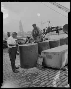 George Perry and Joseph Cronin checking newly poured concrete encasing 30 gallon drums of atomic waste, which will then be loaded on to a barge and taken out to sea to a dumping ground approved by the Atomic Energy Commission