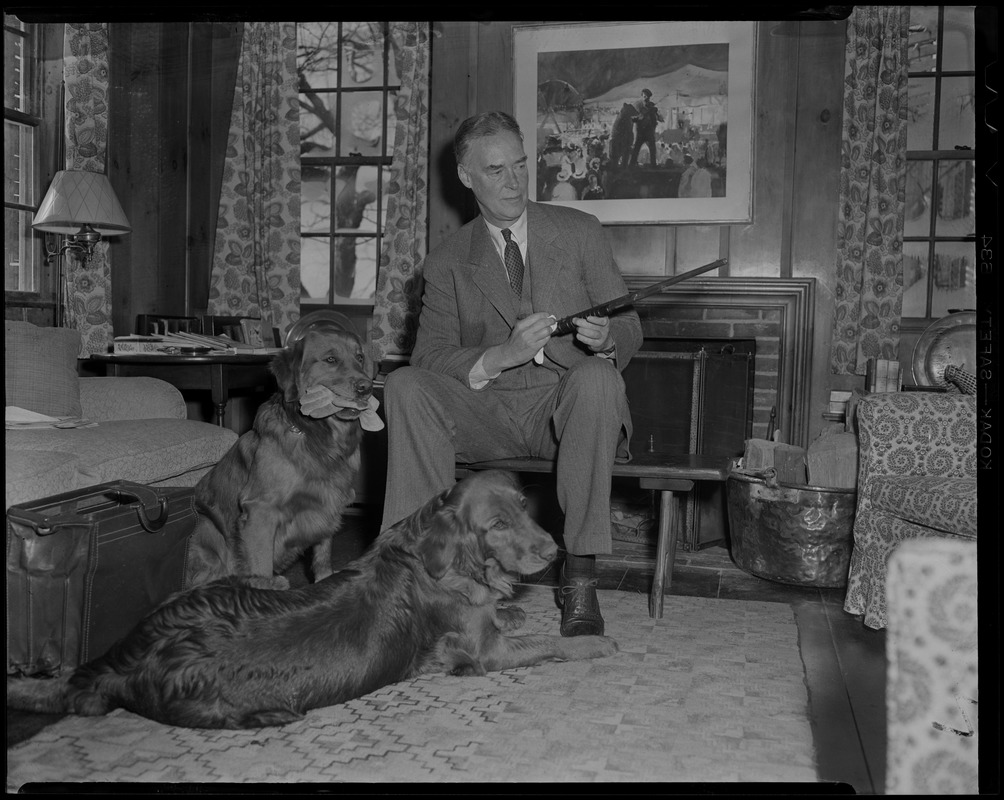 Christian Herter polishing firearm at home with two dogs