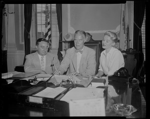 Governor Herter signing document with quill pen as Mary Clayton and other man look on