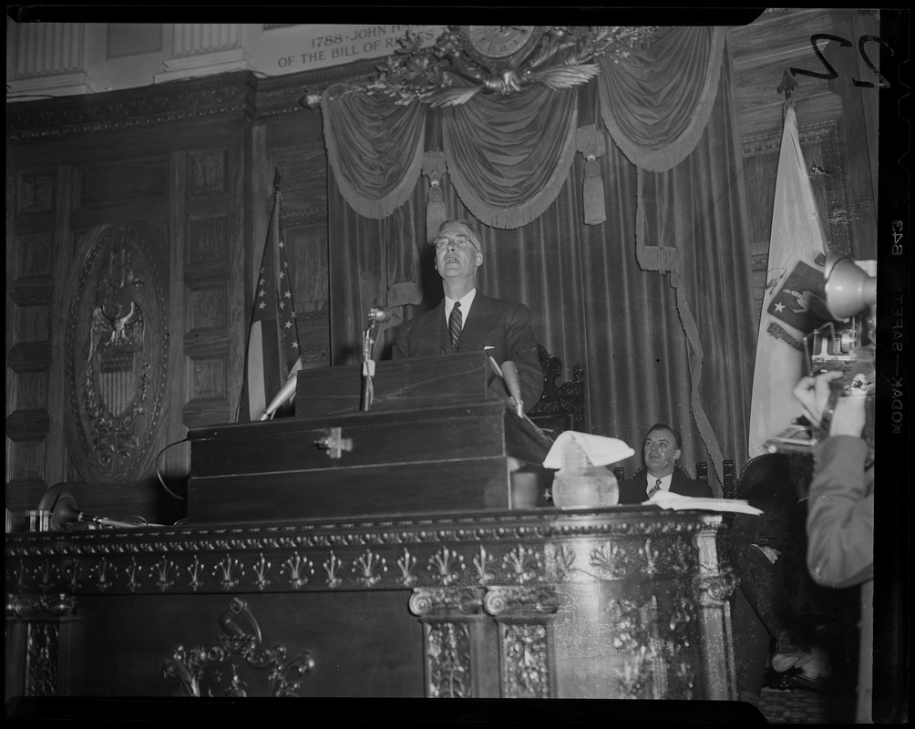 Gov. Christian Herter speaking from podium of House Chamber at State House, with Lt. Gov. Sumner G. Whittier seated behind