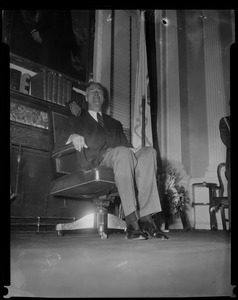 Gov. Christian Herter seated in front of fireplace