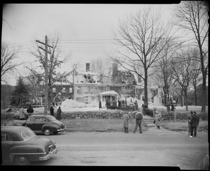 Exterior view of Wayside Inn with its collapsed roof, people, and cars after fire