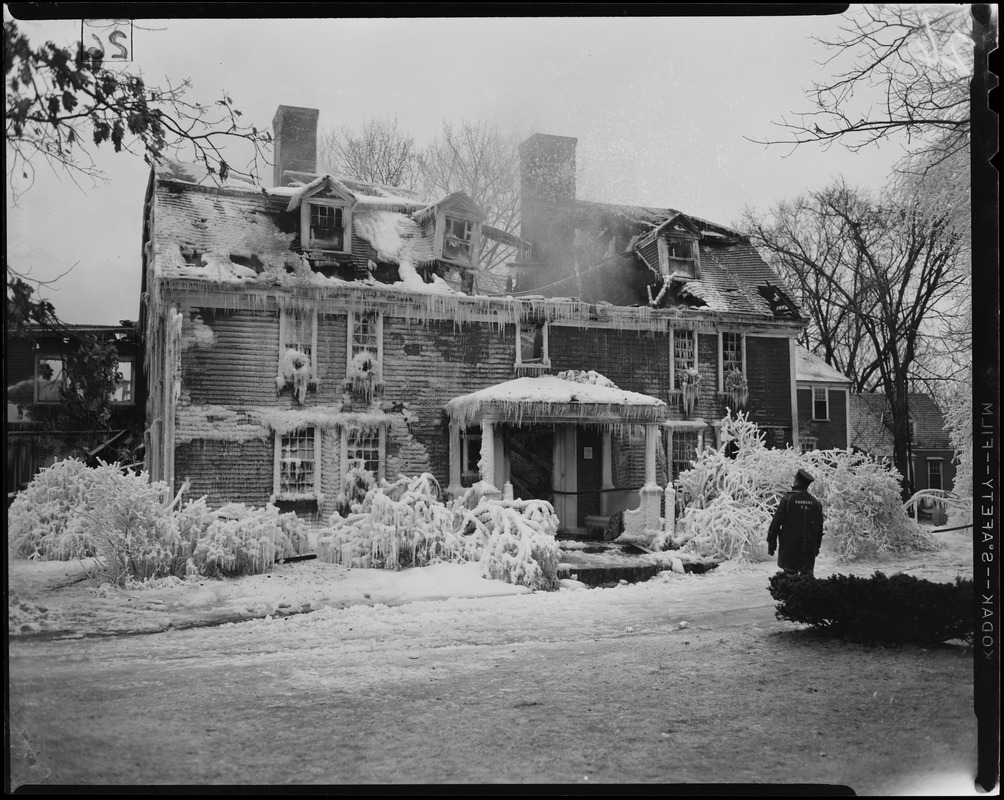 Exterior view of Wayside Inn with collapsed roof and Sudbury Fire Department official after fire