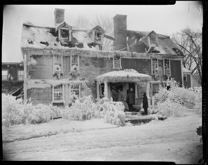Exterior view of Wayside Inn with collapsed roof and three people on front steps after fire