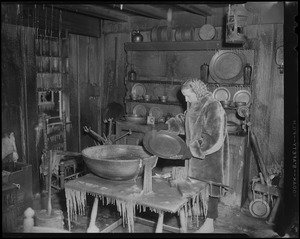 Mrs. Barrie W. Blake holding up a platter in "The Old Kitchen" of Wayside Inn after fire