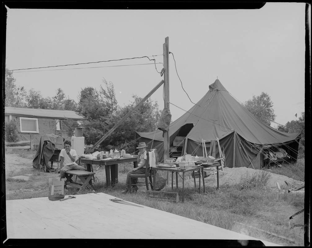 Two boys eating at table outside tent