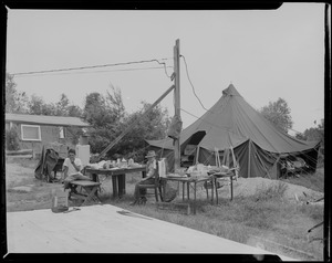 Two boys eating at table outside tent