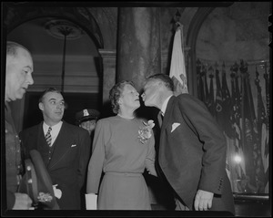 Gov. Christian Herter and Mary Pratt Herter leaning in for a kiss at inauguration, with Lt. Gov. Sumner G. Whittier nearby