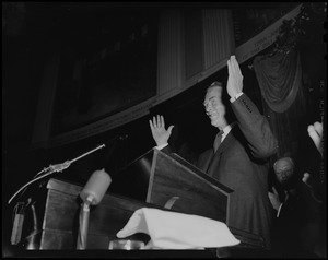 Gov. Christian Herter standing at podium with hands raised