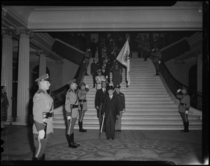 Gov. Christian Herter, man in military uniform, and sergeant-at-arms descending Grand Staircase of State House at inauguration