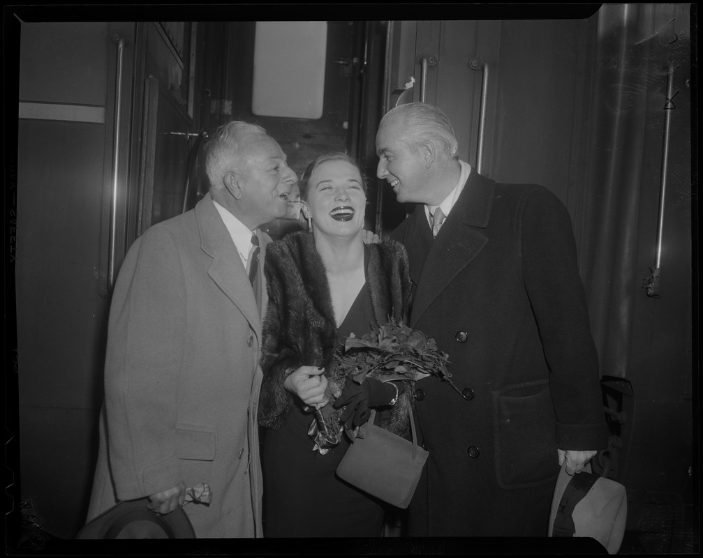 Denise Darcel holding flowers as Reuben Gryzmish and Edward C. Donnelly from March of Dimes campaign lean towards her