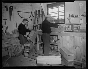 Two men in a workshop building boxes