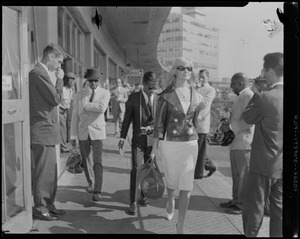 Sammy Davis, Jr., with camera, and May Britt walking past photographers