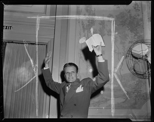 Billy Graham with both hands raised and holding up a Bible