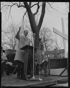 Billy Graham speaking at outdoor podium with large cross nearby