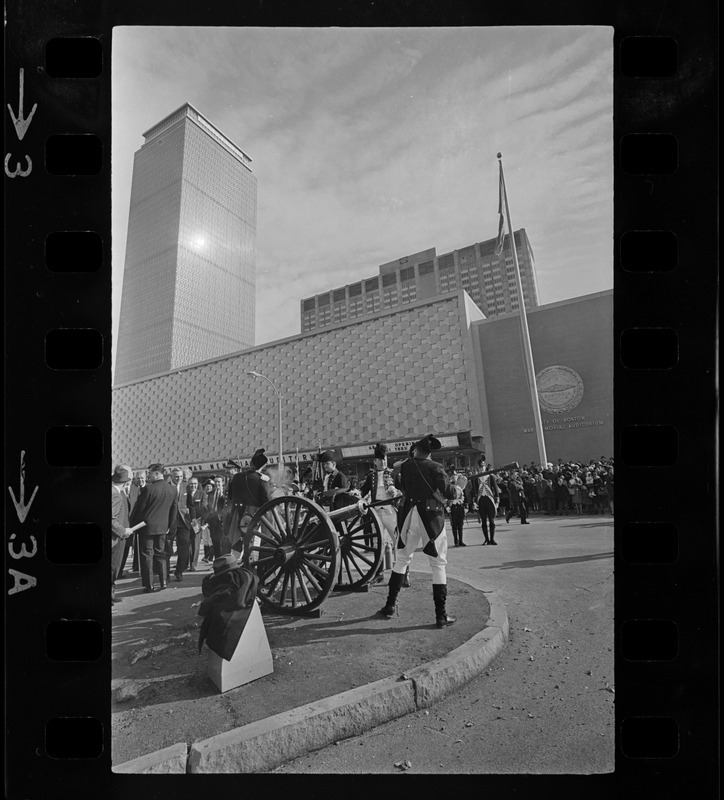 State, city, and federal officials watch as Newport Artillery Company cannon roars out one of 13 rounds saluting the opening of Boston's new War Memorial Auditorium in the Prudential Center, Back Bay, yesterday