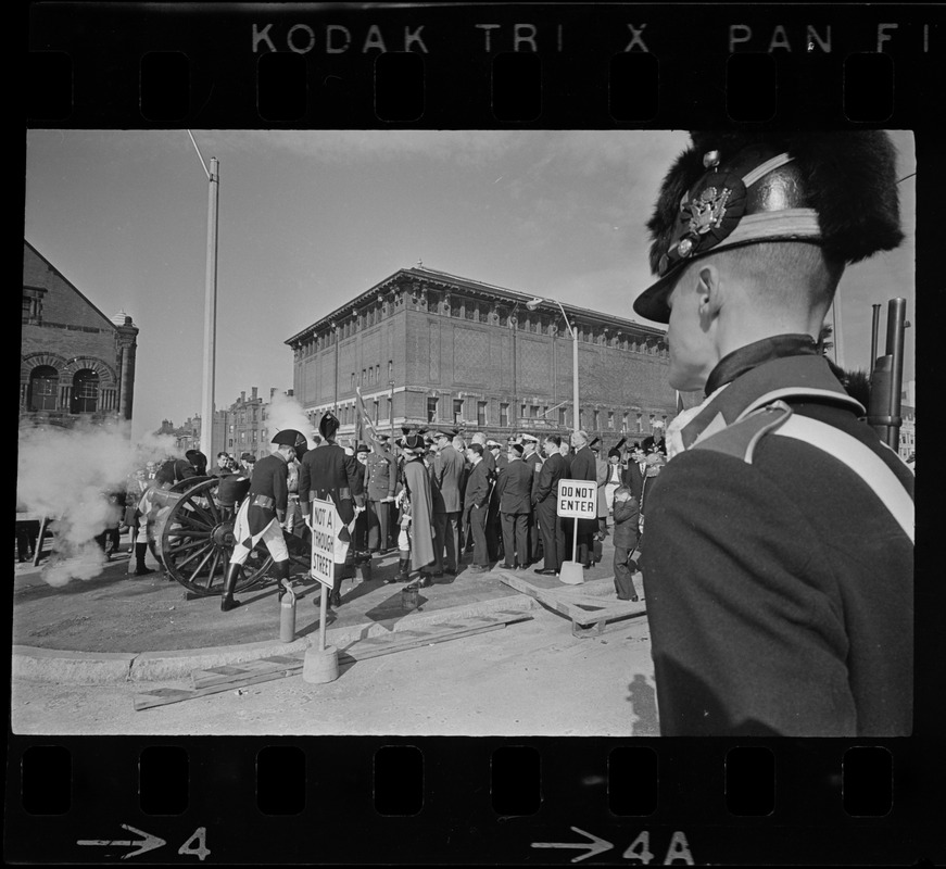 State, city, and federal officials watch as Newport Artillery Company cannon roars out one of 13 rounds saluting the opening of Boston's new War Memorial Auditorium in the Prudential Center, Back Bay, yesterday