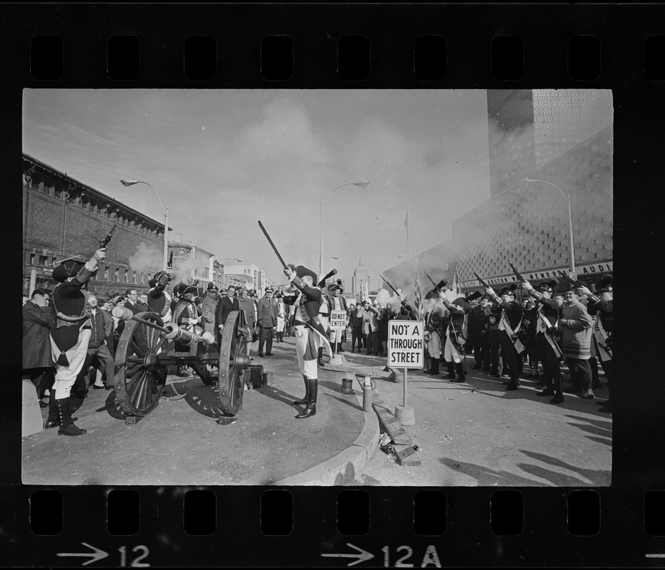 State, city, and federal officials watch as Newport Artillery Company cannon roars out one of 13 rounds saluting the opening of Boston's new War Memorial Auditorium in the Prudential Center, Back Bay, yesterday