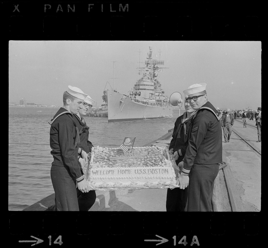 Sailors hold cake as the guided missile heavy cruiser U. S. S. Boston comes alongside pier at South Boston Naval Annex