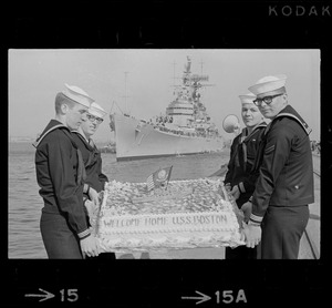 Sailors hold cake as the guided missile heavy cruiser U. S. S. Boston comes alongside pier at South Boston Naval Annex