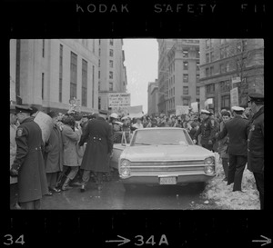 Car carrying Dr. Benjamin Spock leaving the Federal Building in Boston after arraignment of "Boston Five" on charges of aiding draft resisters