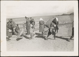 Natives on Okinawa loading rice out of LST 795